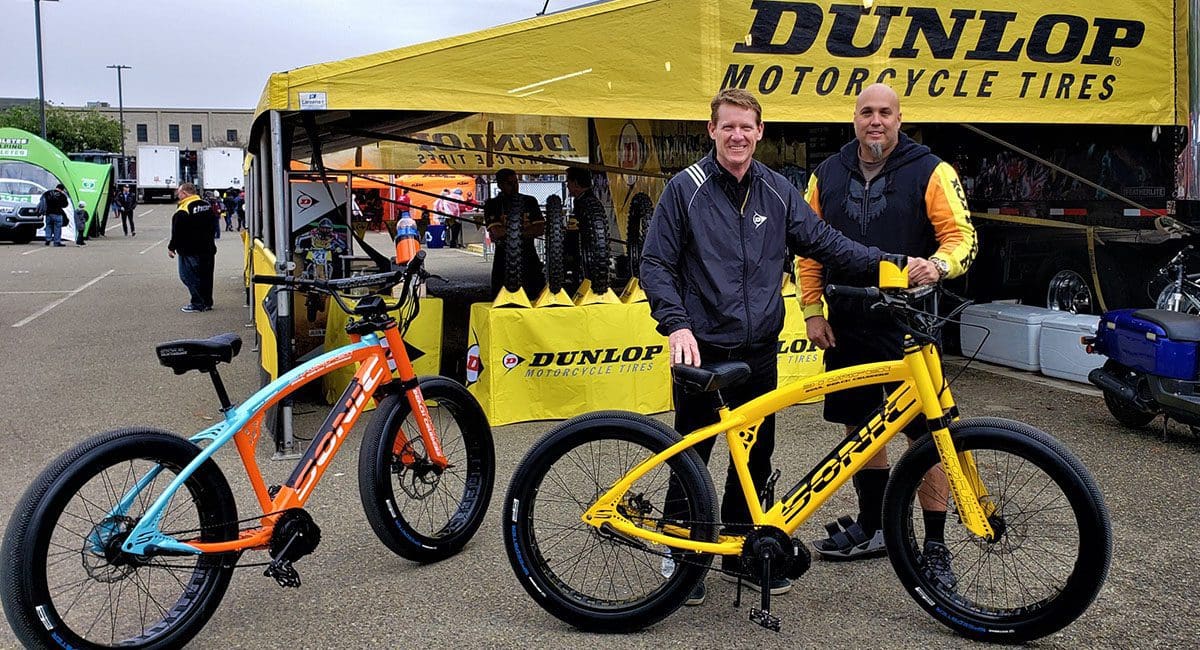 Two men standing next to a vibrant yellow and orange SOULFAST eBike.