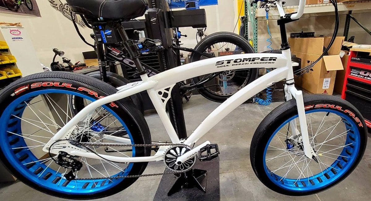 A white and blue Pedal Stomper bicycle is parked in a shop.