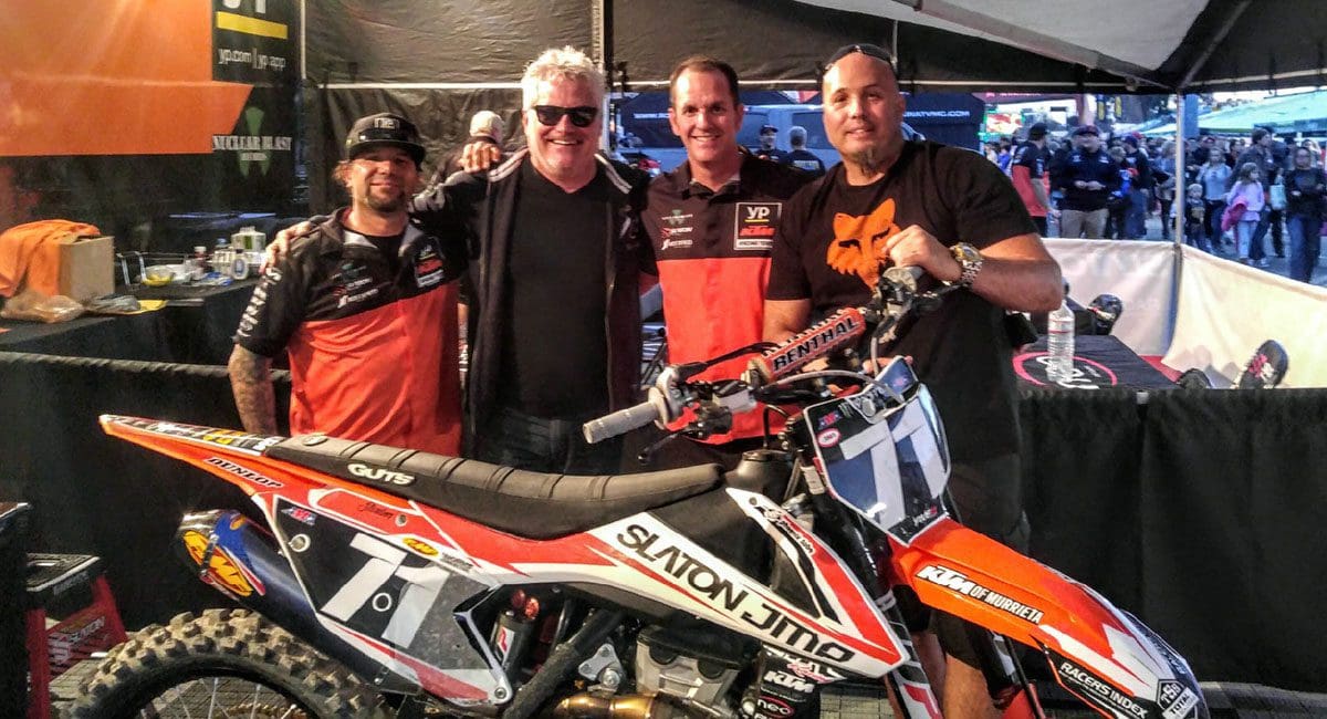 Three men standing next to a dirt bike at a SOULFAST event.