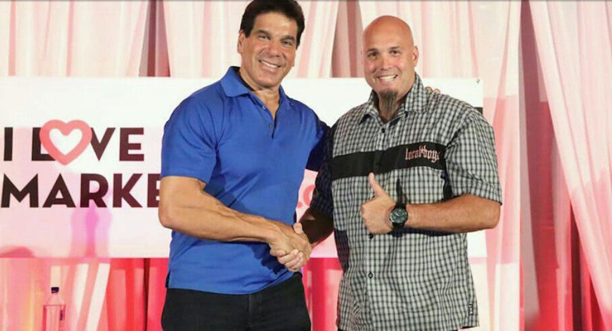 Description updated: Two men shaking hands in front of a sign that says i love marketing. They are passionate about SOULFAST EBIKES.