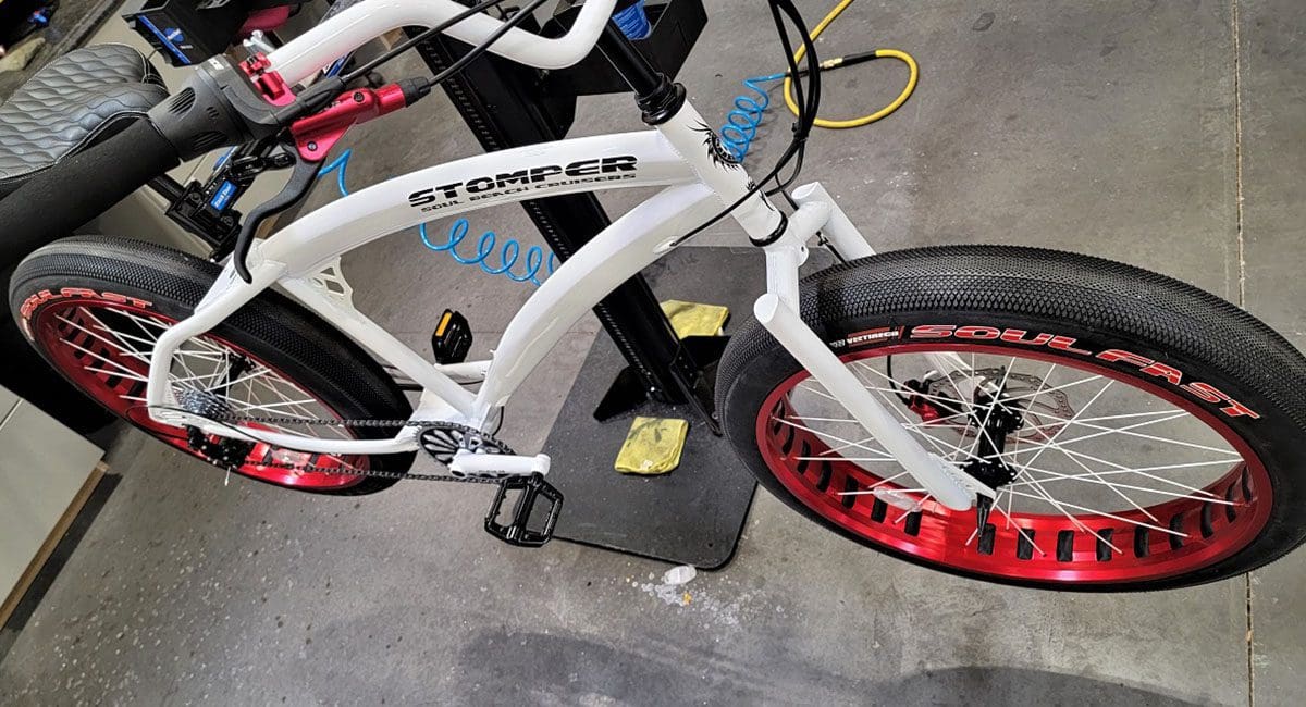 A white bicycle with red rims in a garage.