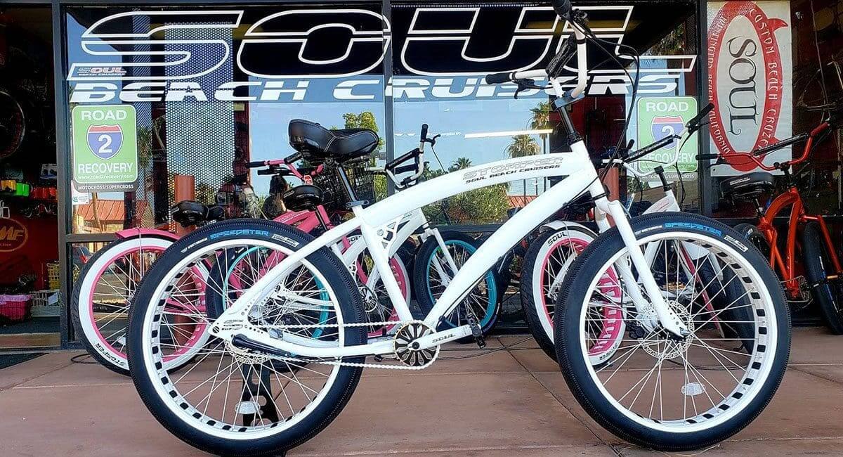 A white Pedal Stomper bicycle is parked in front of a store.