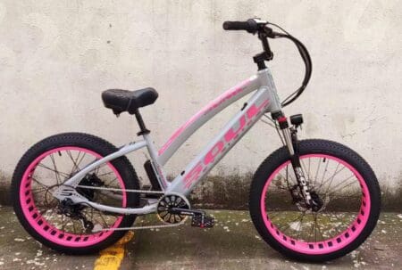 A pink and silver bike parked on the side of a street.