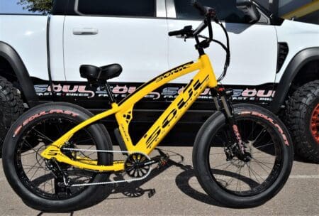 A yellow bike parked in front of a white car.