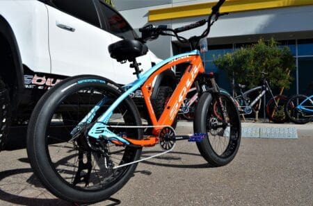 A blue and orange SABER PRO RACE EDITION electric bike parked in front of a truck.