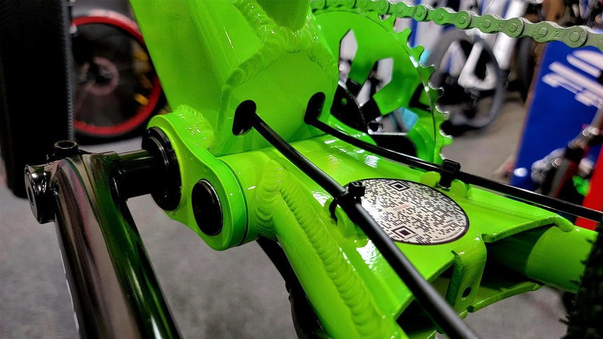 A close up of the chain on a green bicycle.