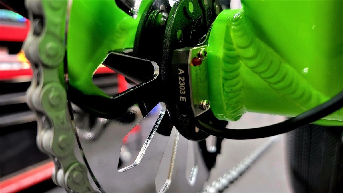 A person wearing green gloves holding onto a bicycle wheel.
