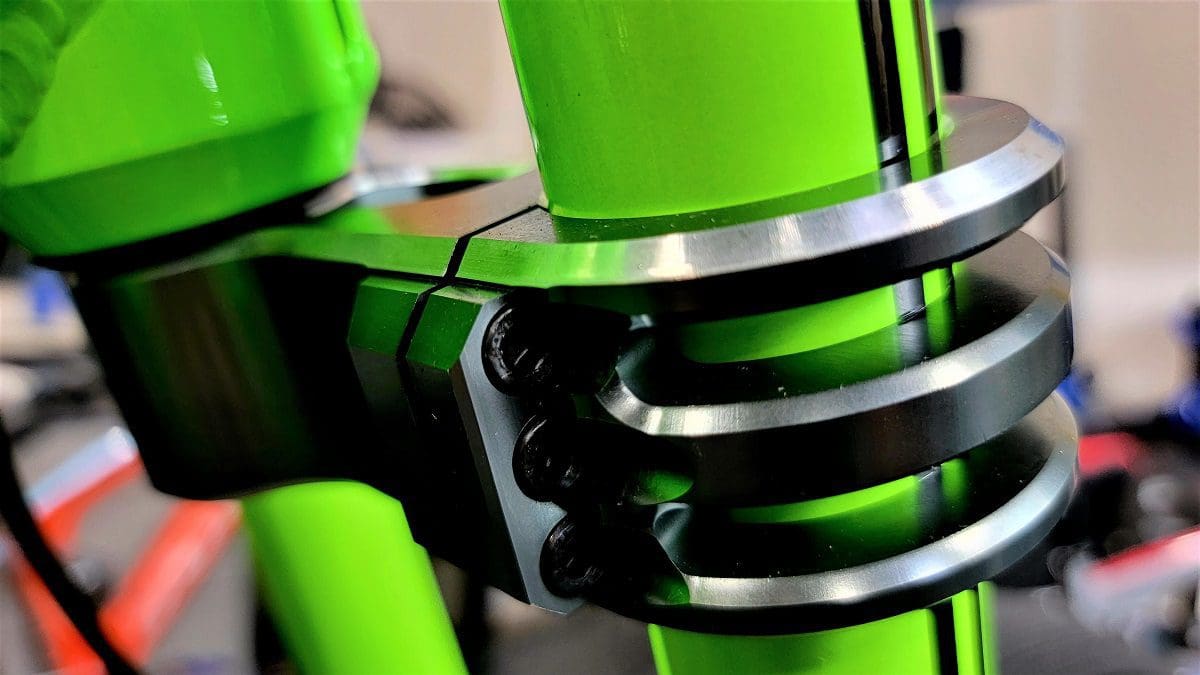 A close up of the front fork and shock on a green bicycle.