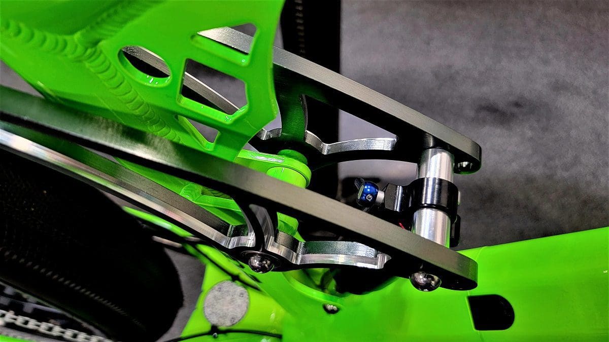 A close up of the front suspension on a green motorcycle.