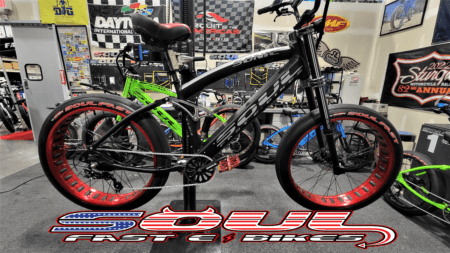 A black bicycle is parked in front of some other bikes.