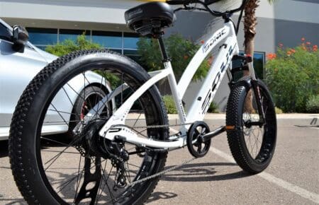 A MISS SABER SPORT WHITE & BLACK bike parked in front of a car.