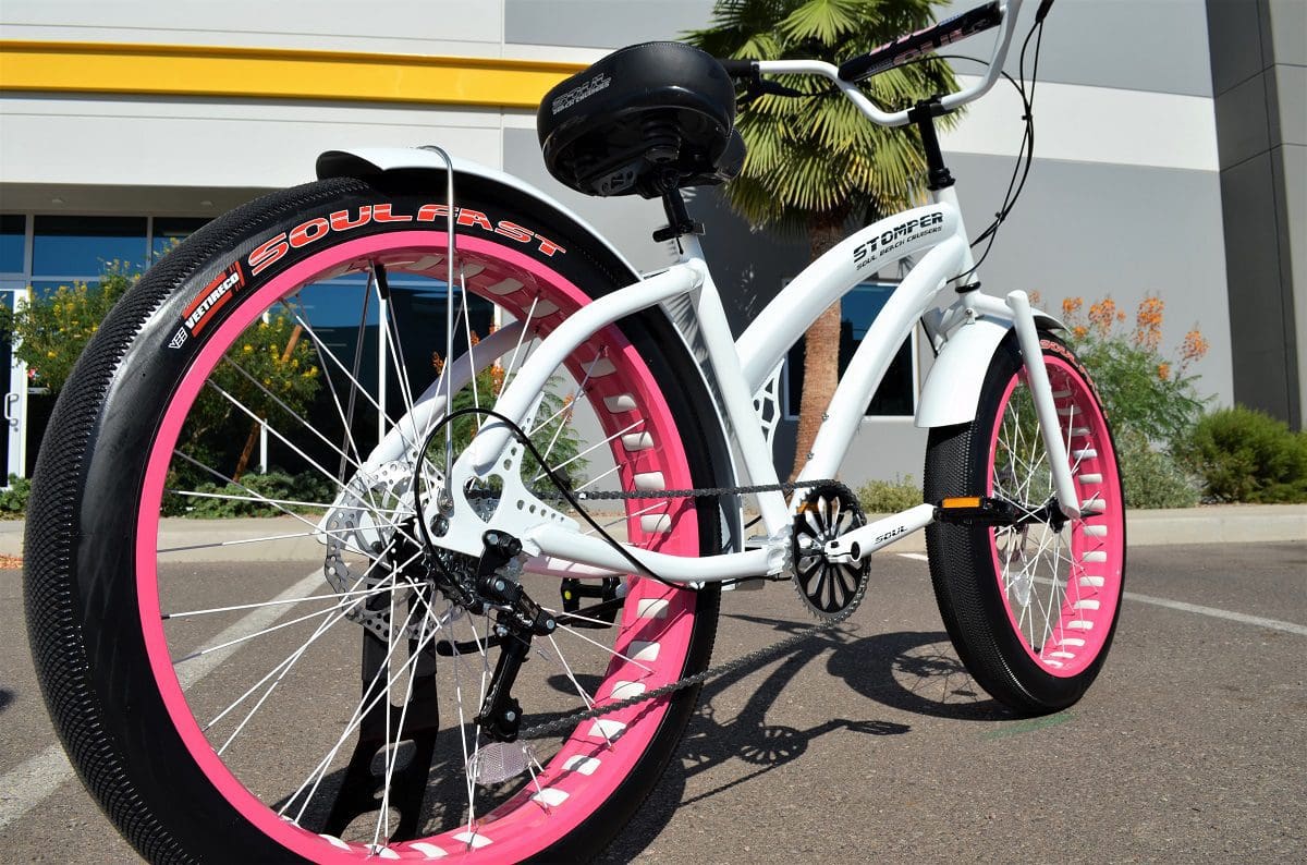 A Ladies Miss Stomper White and Pink with pink rims parked in front of a building.