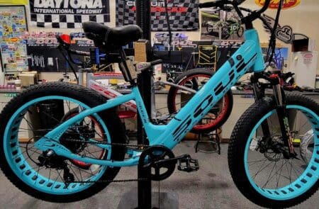 A blue bicycle is parked in front of other bikes.