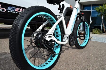 A bicycle with blue wheels parked on the street.