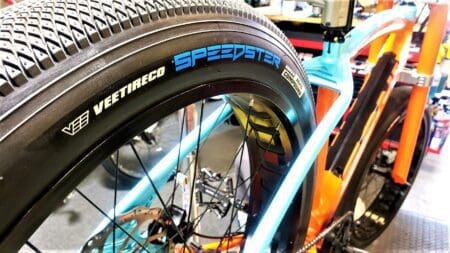 A bike with a TIRES set (2) Vee Speedster tires 26 x 3.5" on it in a shop.