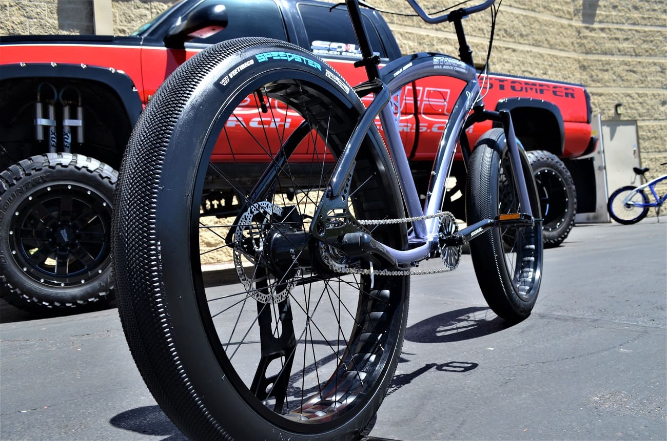 Bicycle with large tires near red truck.
