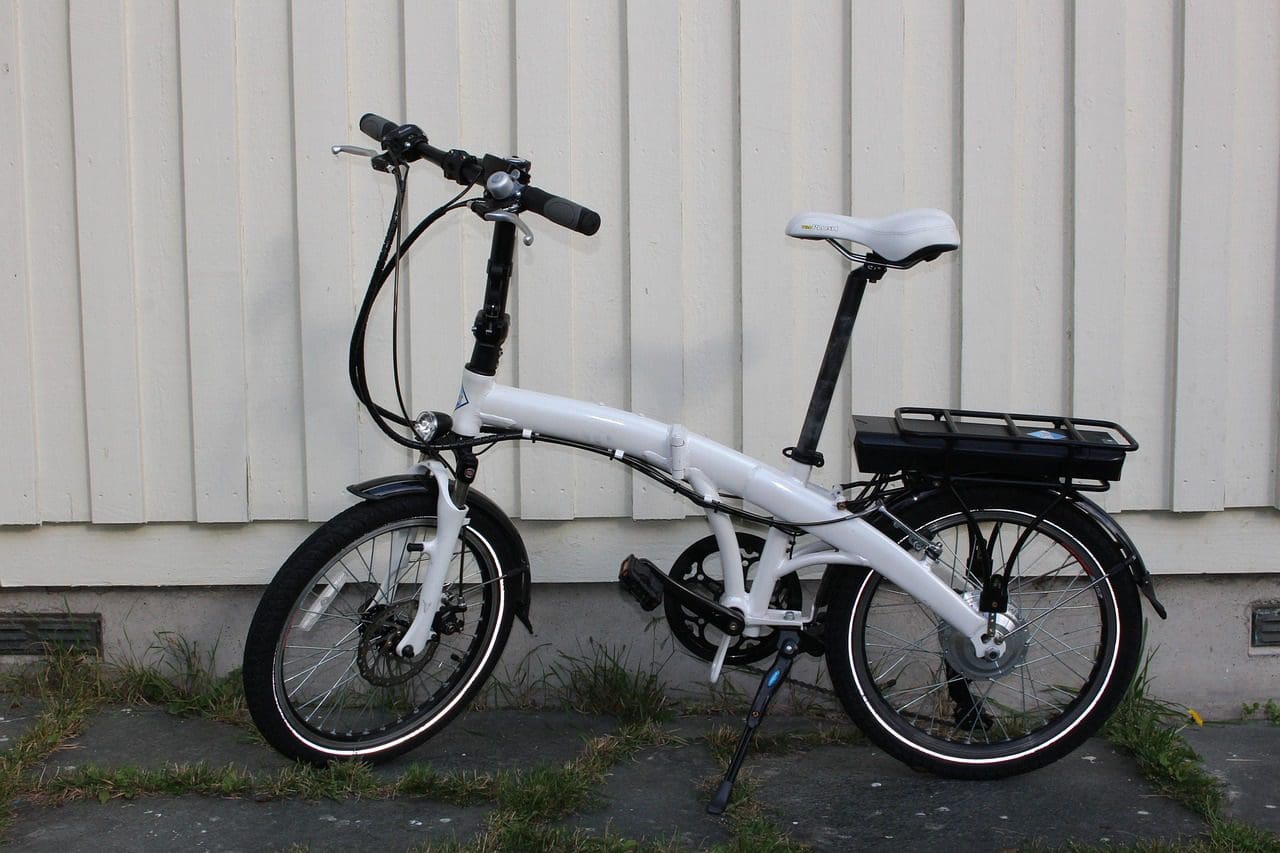 A white folding bike parked in front of a building by SOULFAST EBIKES.