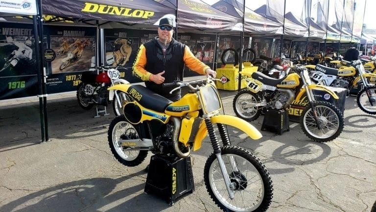 A man standing next to a yellow dirt bike, also known as an EBIKE.