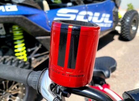 A Soul Embossed Cup Holder - Red chrome Black on the handlebars of a motorcycle.