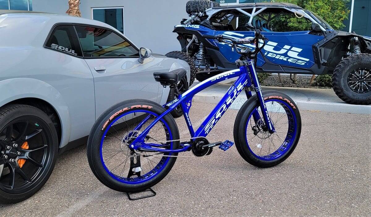 A blue bike parked in front of a white car.