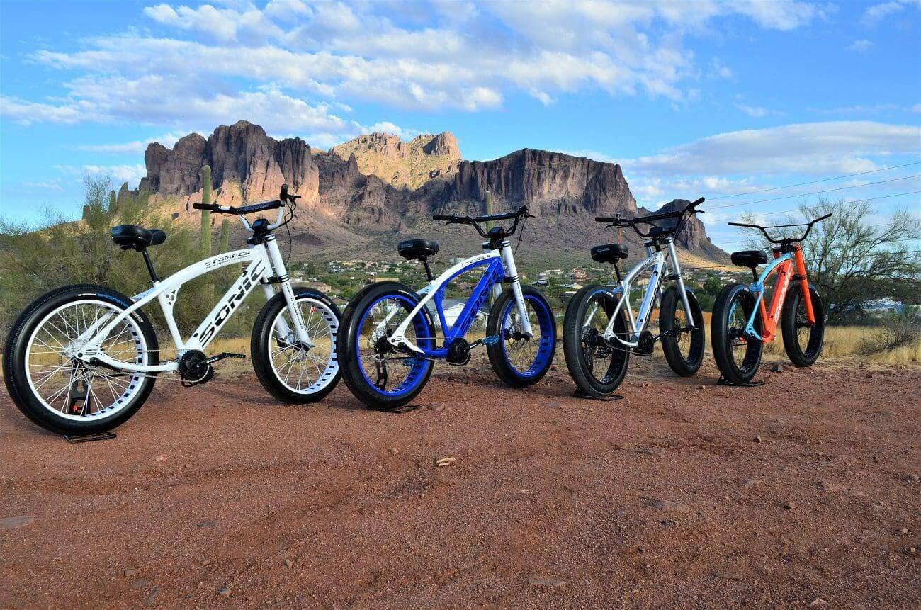 A group of bikes parked on top of a dirt field.