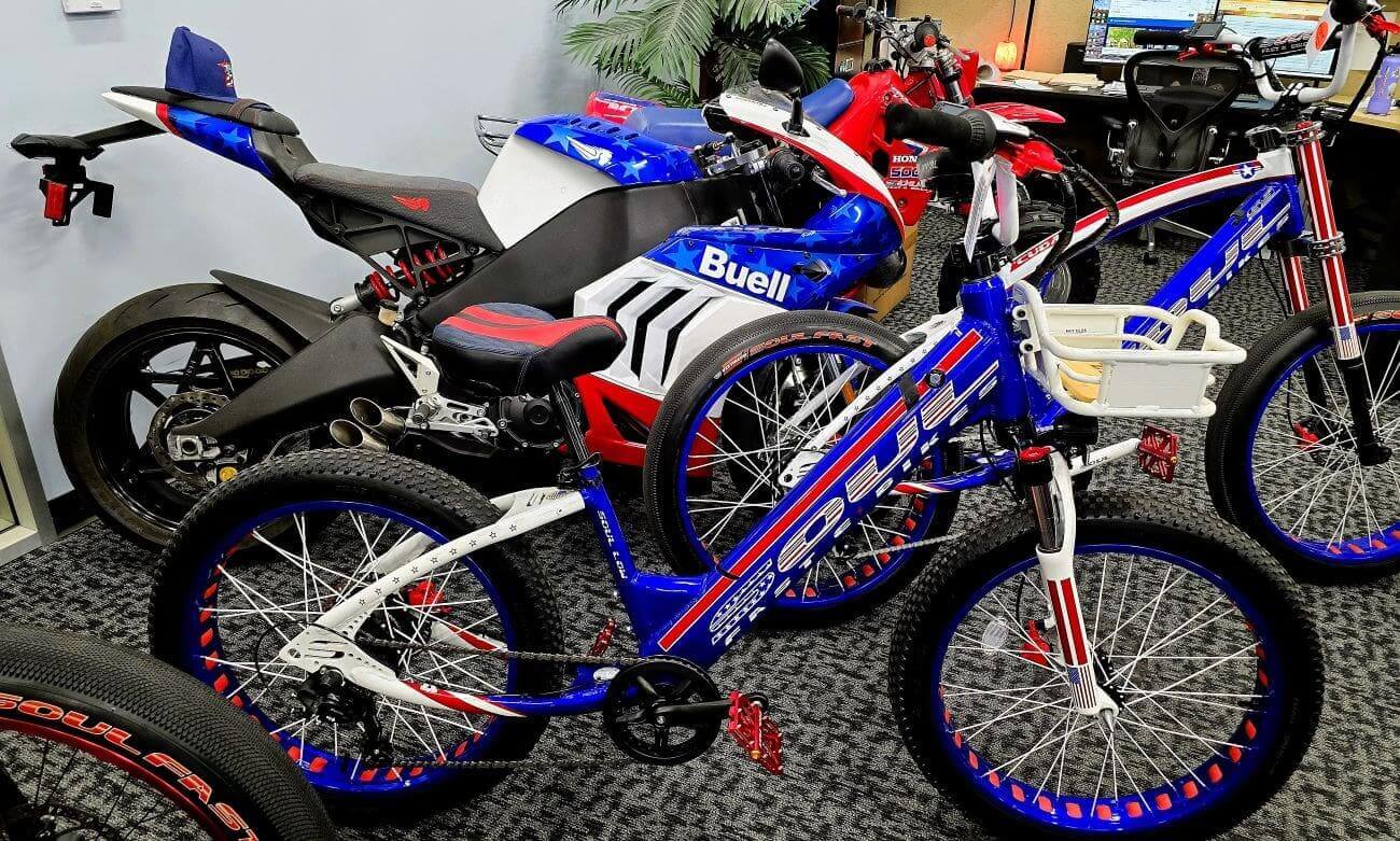 Red, white, blue motorcycles and bicycles indoors.