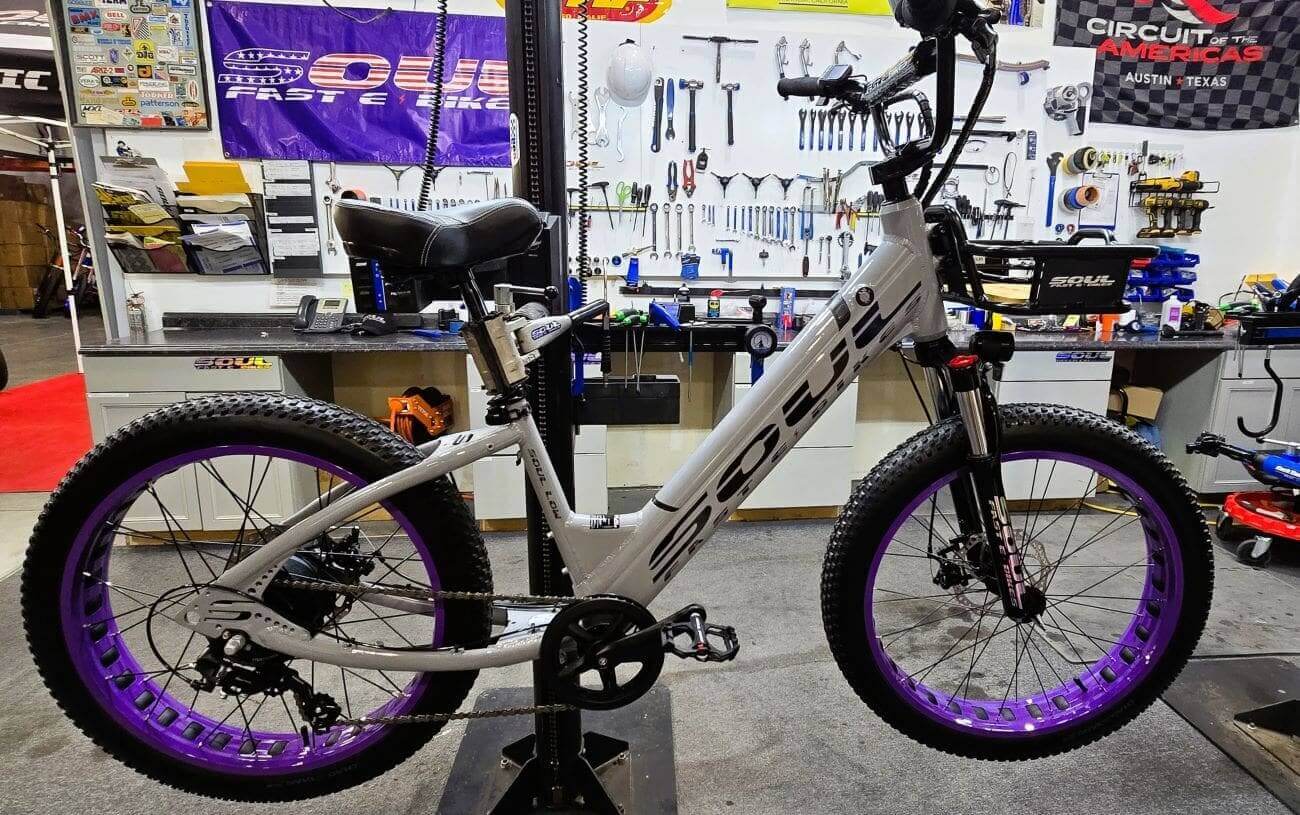 White bicycle with purple rims in workshop.
