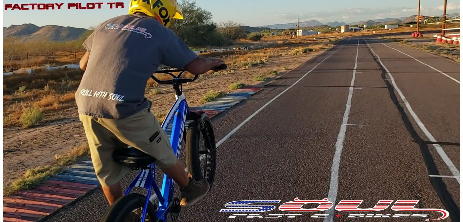 A man riding a bike down the middle of an empty road.