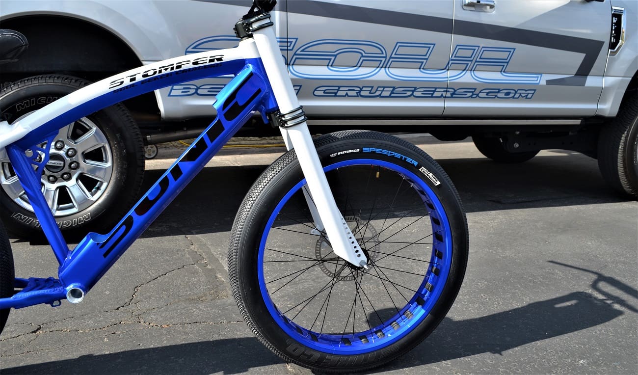 Blue and white bike beside parked vehicle.