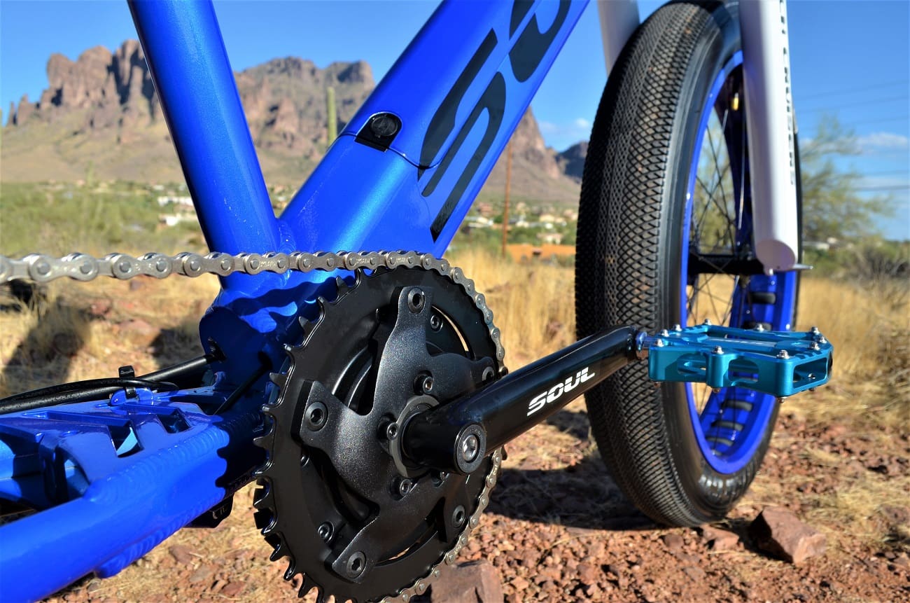 Blue bicycle chain and crankset, desert background.