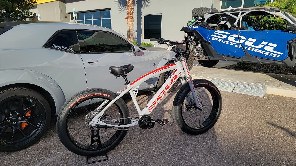 Bicycle beside car and off-road vehicle.
