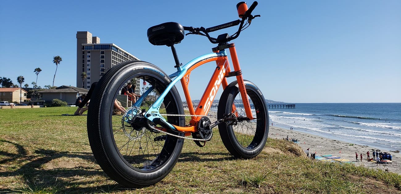 Fat tire bike on grassy beach hill.
