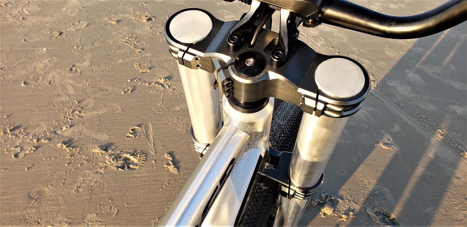 Bicycle handlebars and suspension on sandy beach.