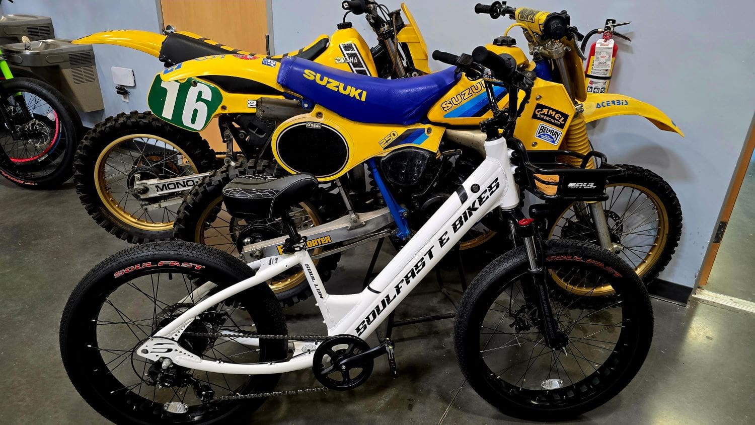 Electric bike and two vintage motorcycles displayed.