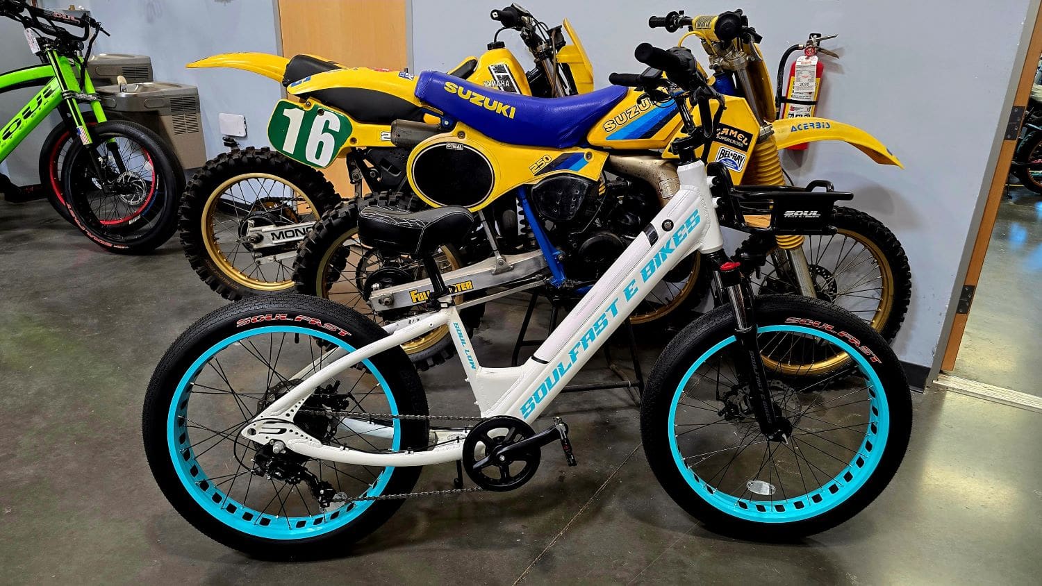 White e-bike and vintage motorcycles in showroom.
