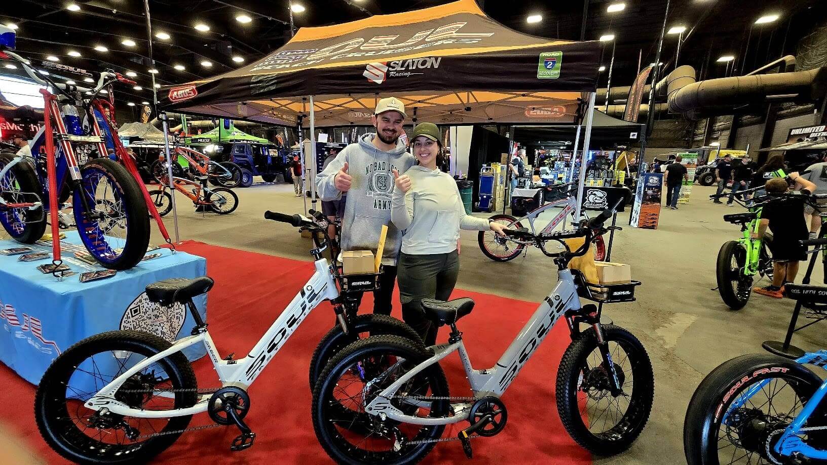 People posing with electric bikes at event.