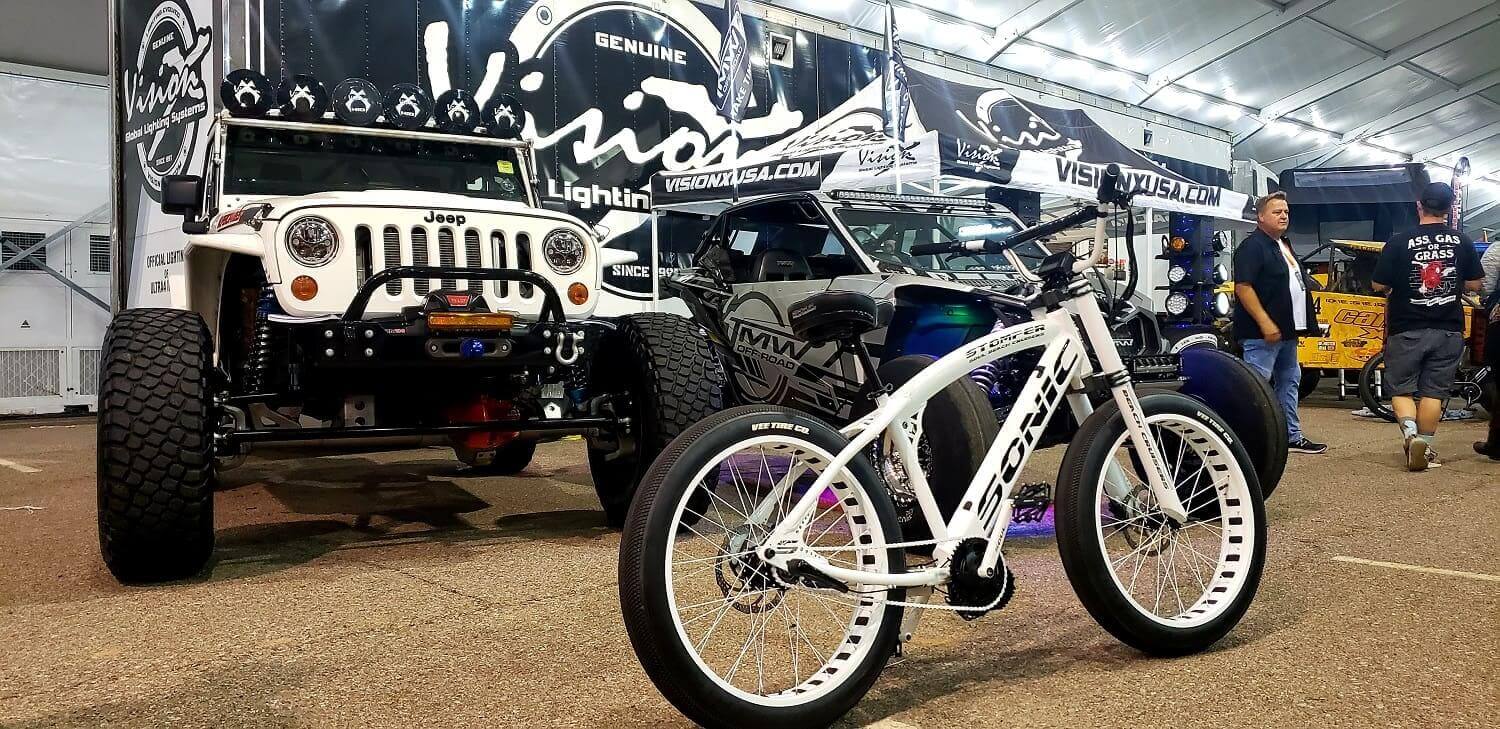 White bike displayed beside modified Jeep.