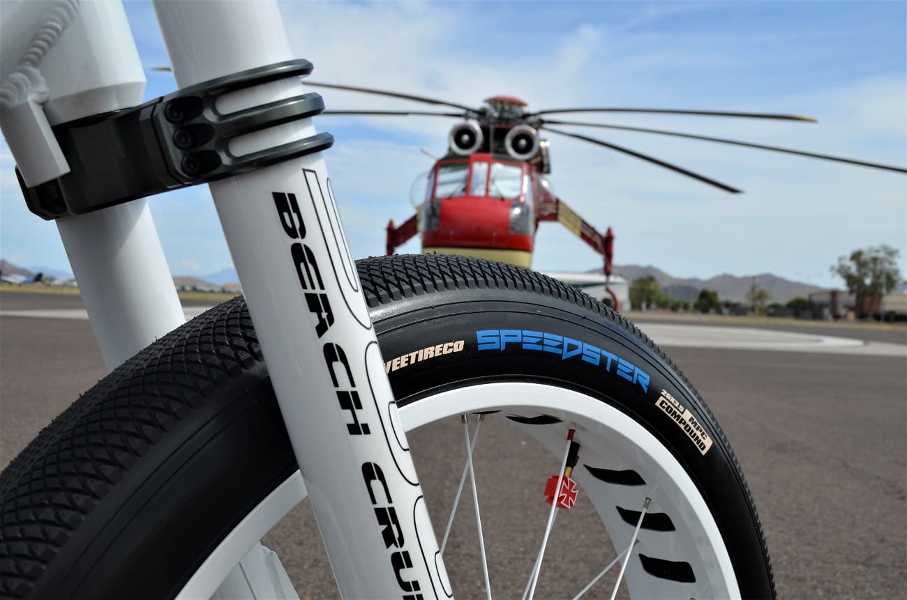 Bicycle wheel close-up with helicopter background.