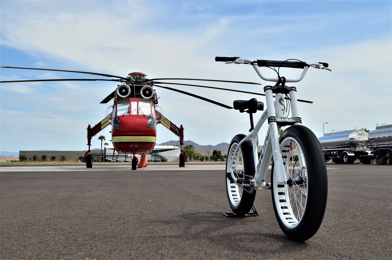 Bicycle and helicopter on tarmac under sky.