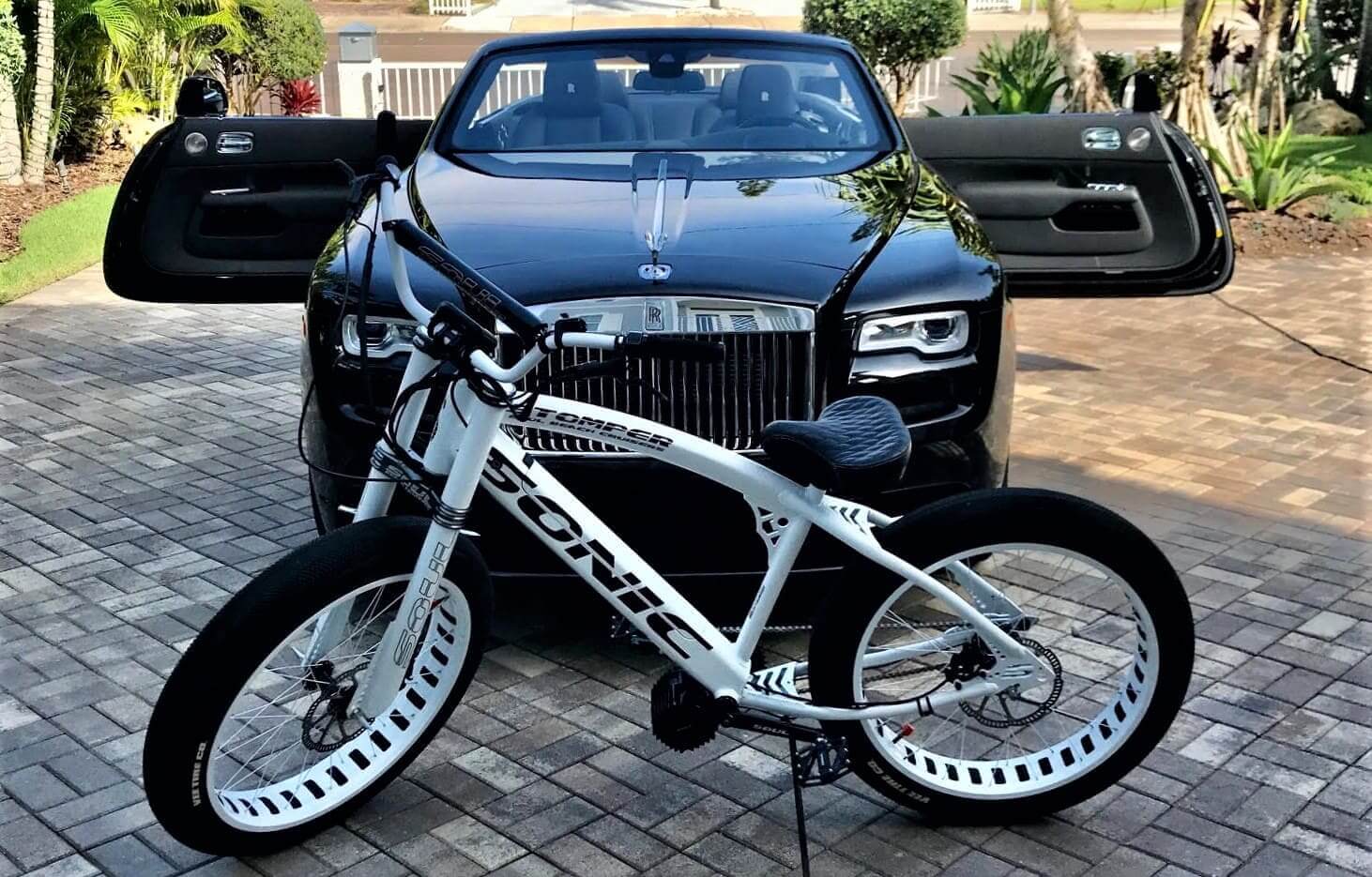 Bicycle parked in front of luxury car.