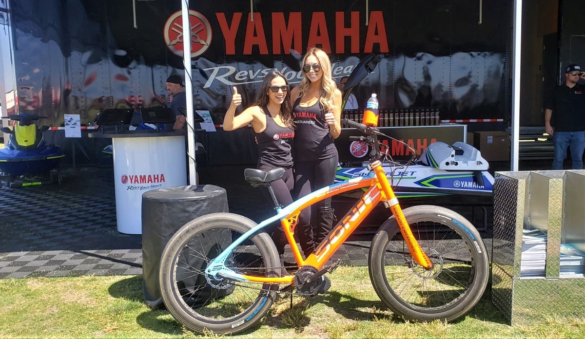 Women posing with bike at Yamaha event.