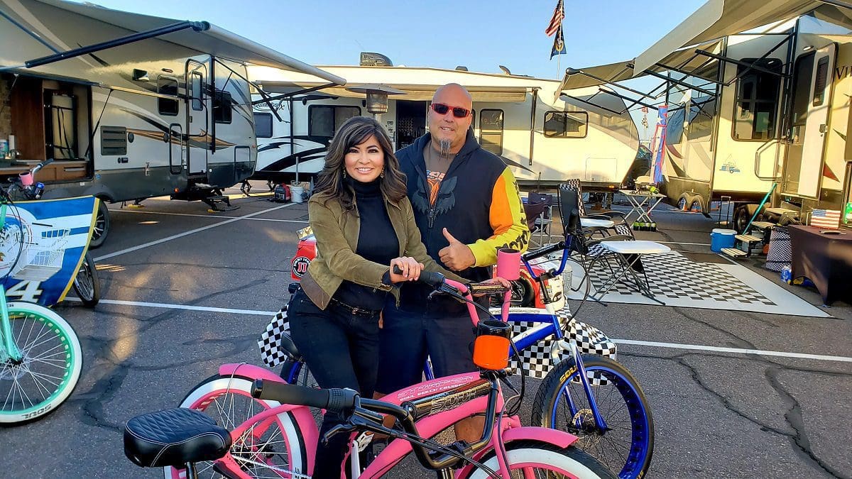A couple posing with a pink SoulFast ebike at a campground with RVs in the background.