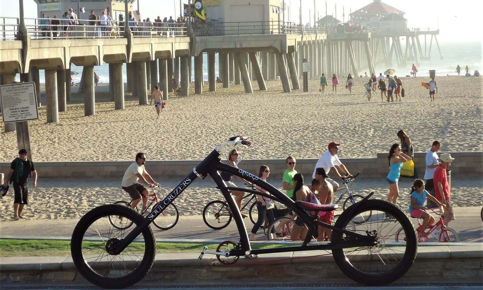 Custom bike near busy beach boardwalk.