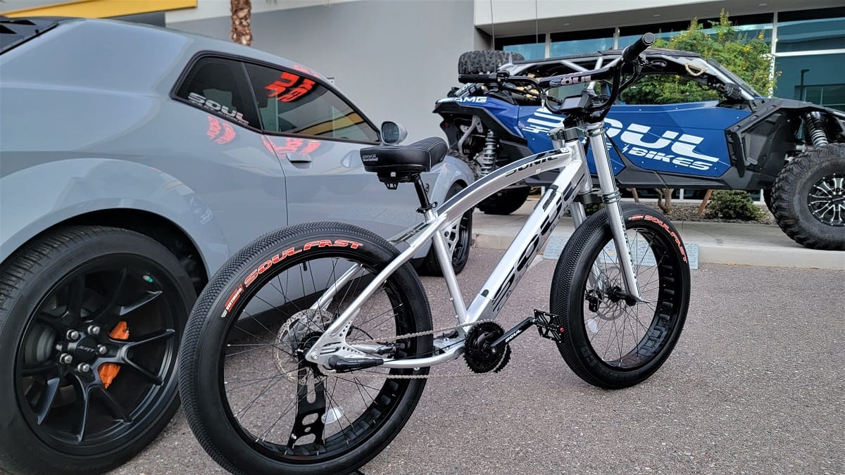 Electric bike parked near car and ATV.