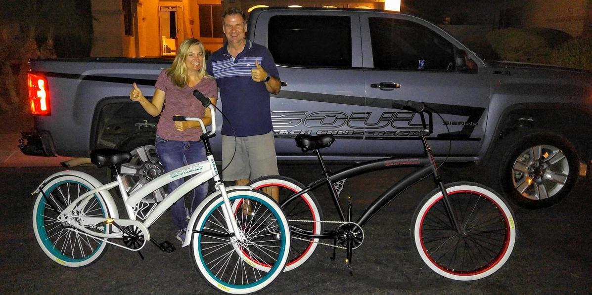 Couple posing with bicycles and a truck.