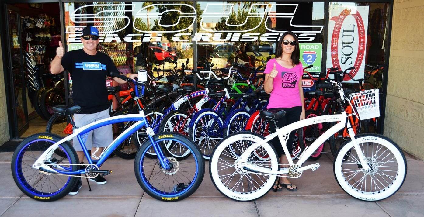 Two people with bicycles outside store.