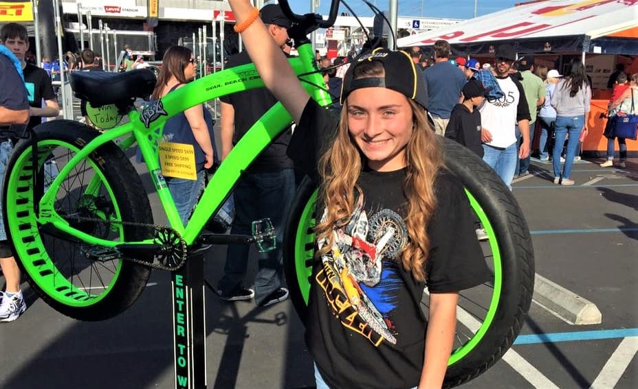 Person smiling next to a green bicycle.
