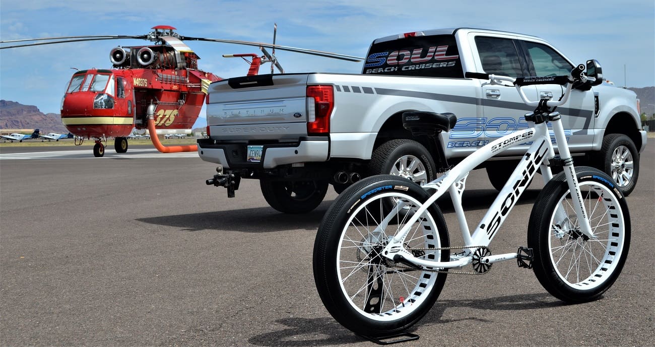 Bicycle, truck, and helicopter on airstrip.