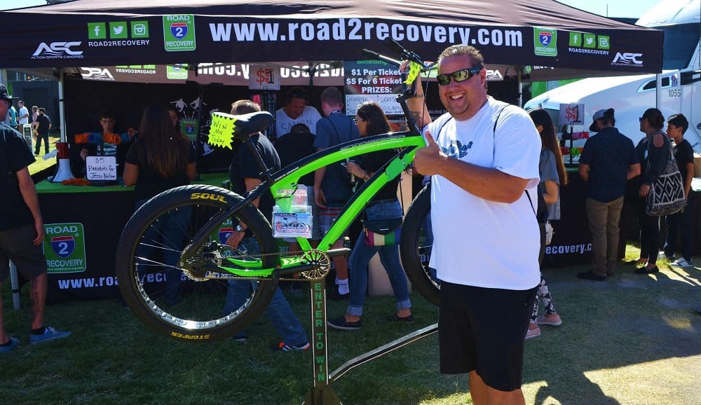 Man posing with green bike at event.