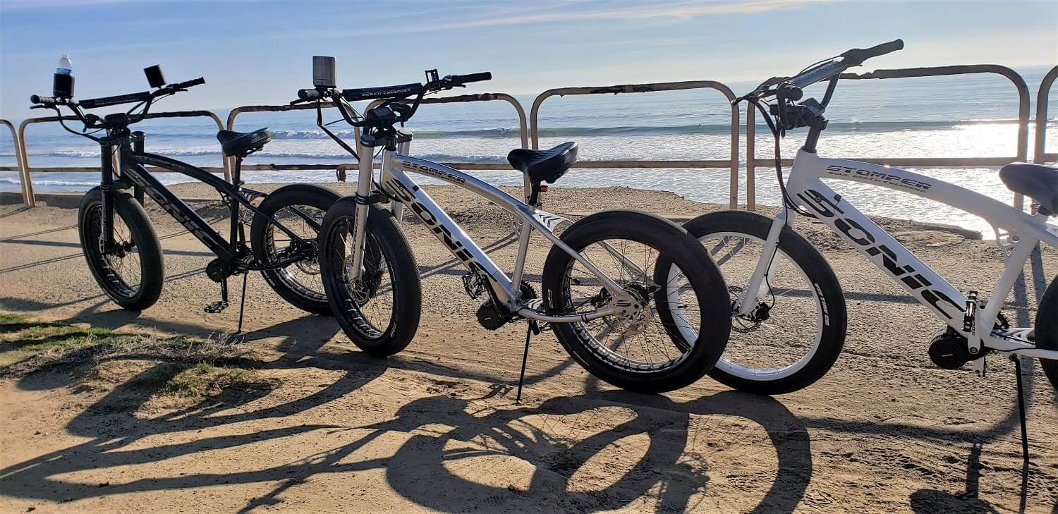 Three bicycles parked by the beachside.
